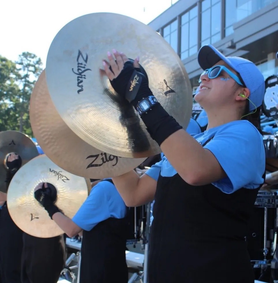 Picture of a band member at a football game holding Cymbals