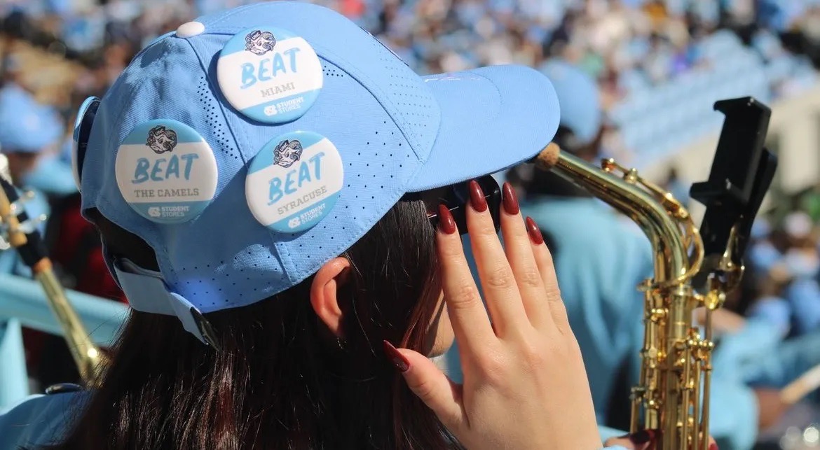 Picture of a band member at a football game wearing a blue baseball hat